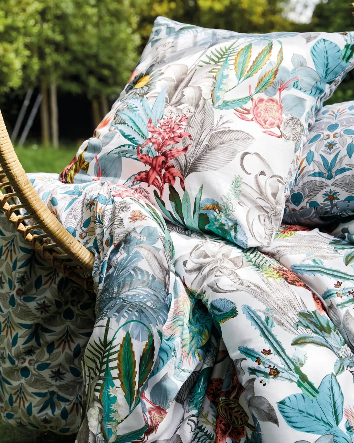 Ensemble de couette à imprimé botanique avec un feuillage vibrant en teal, rose et vert sur fond blanc.