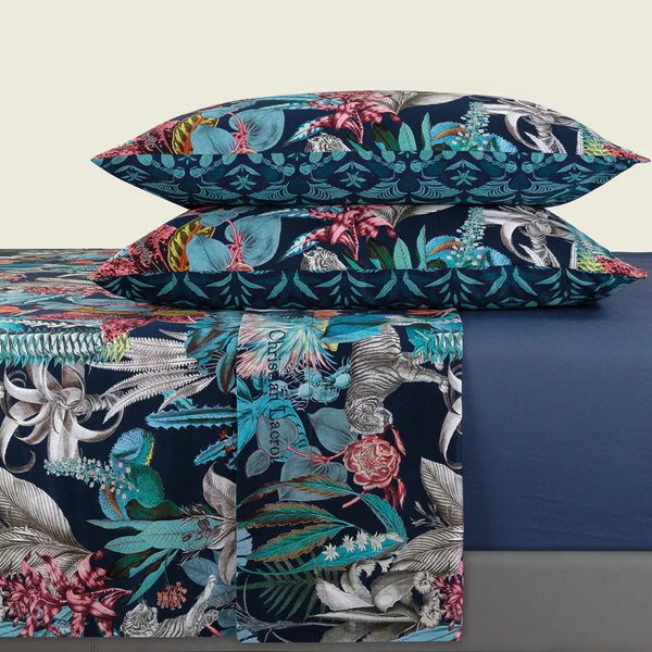 Ensemble de literie aux couleurs vives à thème tropical, présentant des motifs floraux et fauniques audacieux sur une base bleu marine profonde, avec des accents de turquoise, rose et argent.