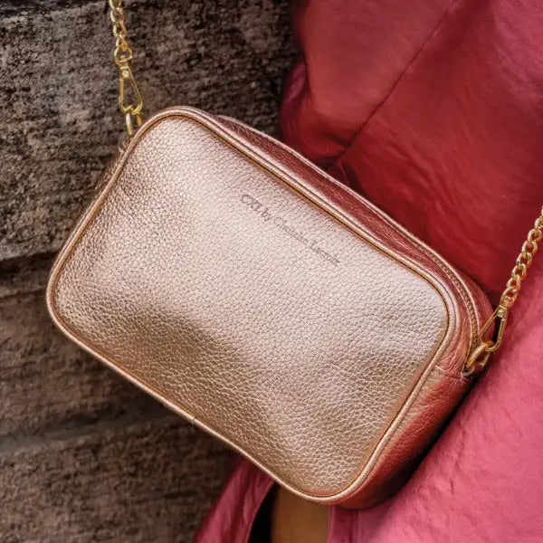 Un sac bandoulière en cuir texturé rose doré avec une sangle chaîne.