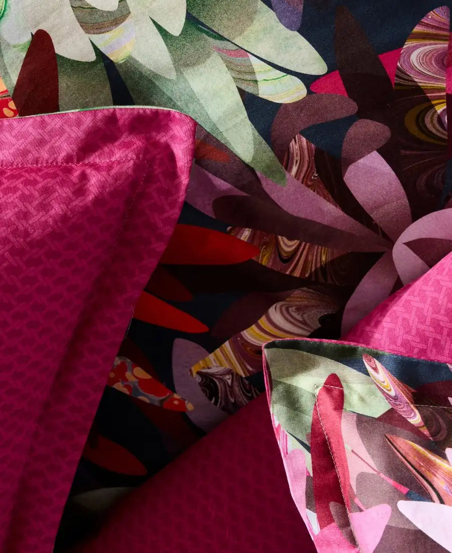 Tissu satiné fuchsia vibrant avec un tissage géométrique subtil, superposé sur un imprimé abstrait audacieux présentant des verts tourbillonnants, des violets et des tons marbrés.