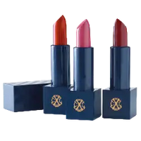 Trois tubes de rouge à lèvres vibrants dans des étuis bleu foncé avec des logos en relief dorés, mettant en valeur des teintes audacieuses de rouge et de rose.